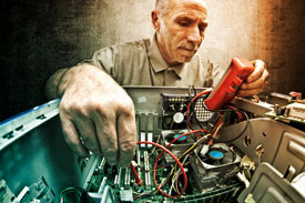 Elderly man checking electric current in a refurbished computer